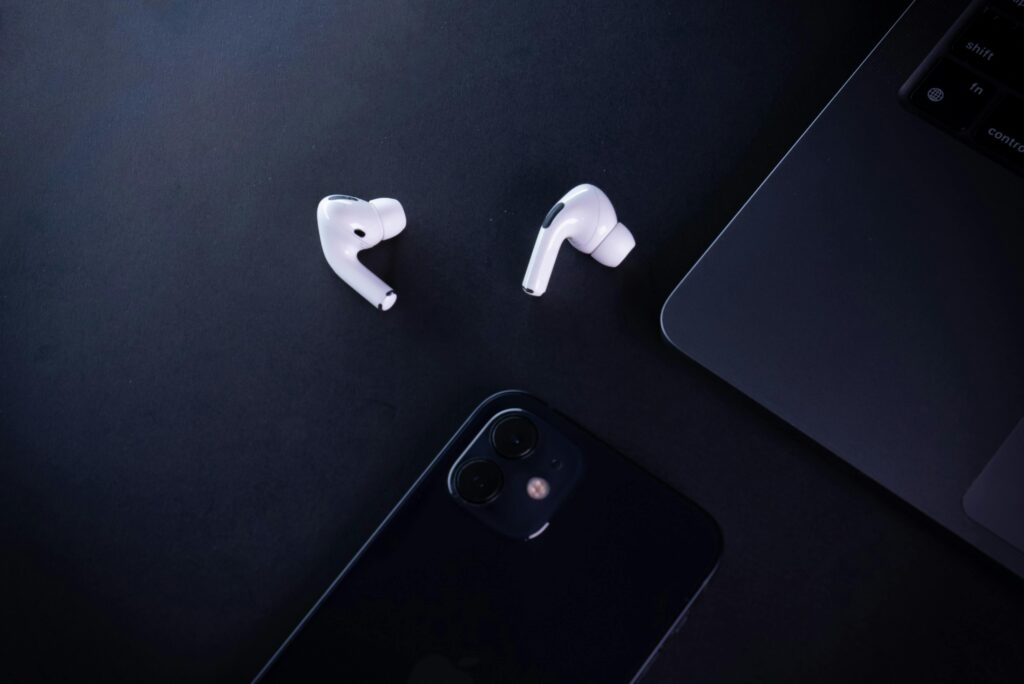 Minimalist workspace featuring earphones, smartphone, and laptop, perfect for tech lovers.