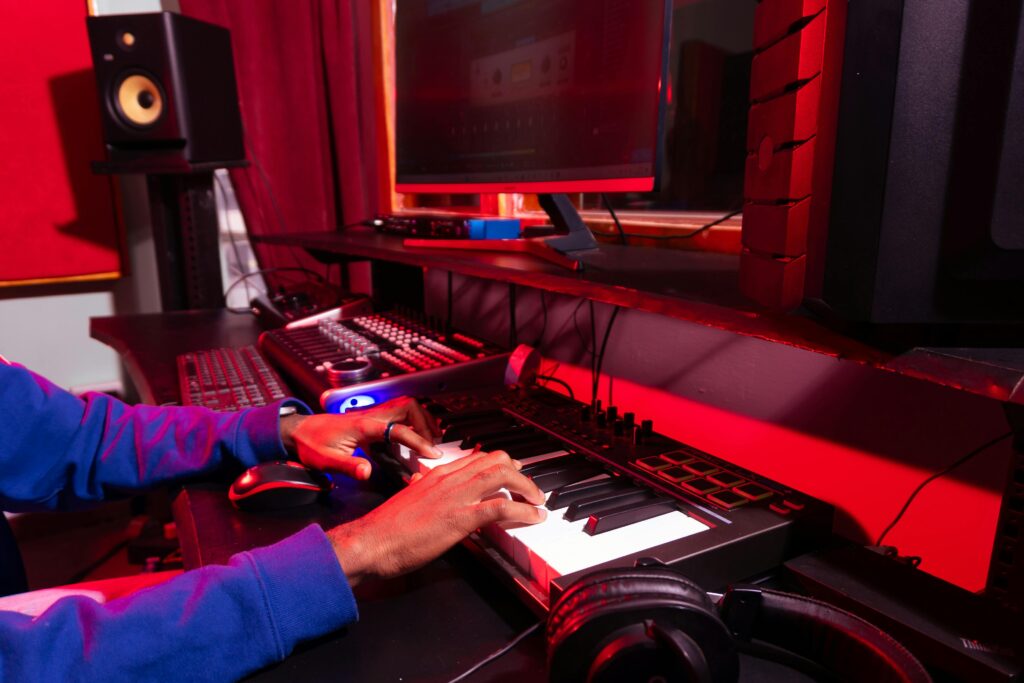 A person creating electronic music in a modern studio using a MIDI controller and computer.